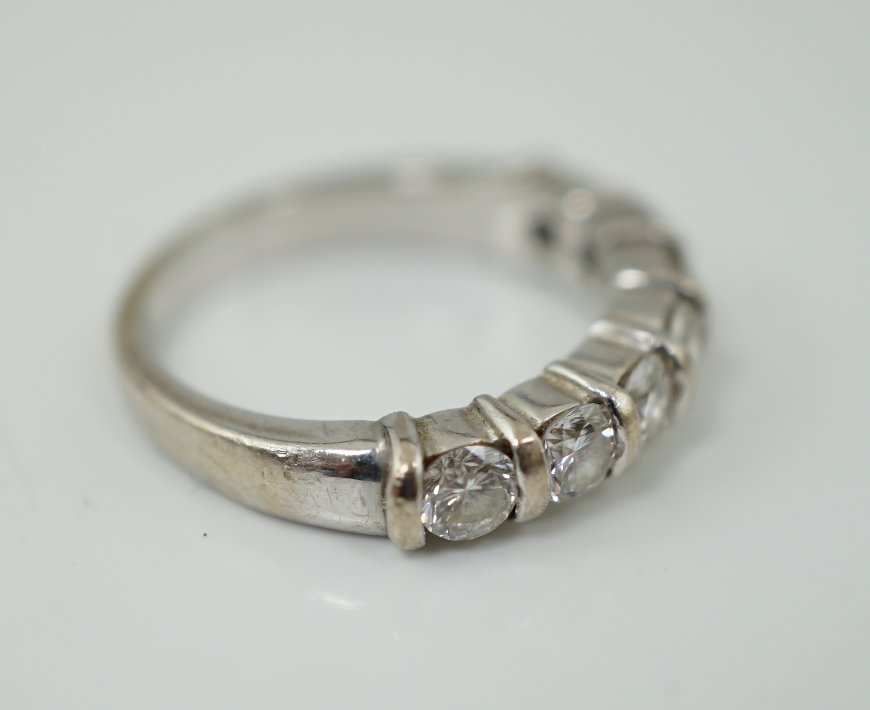 A modern 18ct white gold and seven stone round brilliant cut diamond set half hoop ring